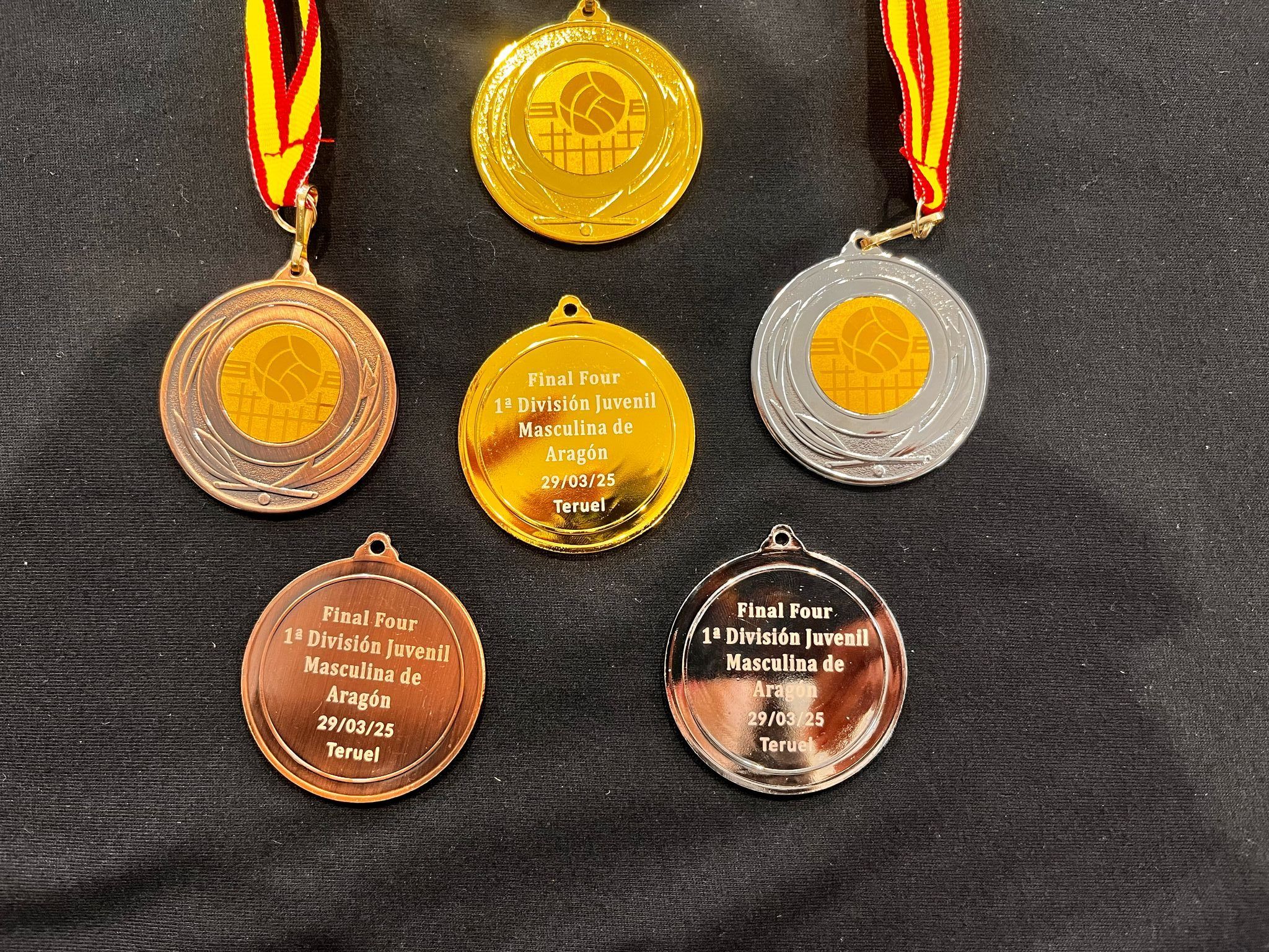 Medallas doradas, plateadas y bronce conmemorativas del torneo "Final Four 1ª División Juvenil Masculina de Aragón", celebrado el 29 de marzo de 2025 en Teruel. Grabado personalizado sobre fondo metálico y cintas con los colores de Aragón.