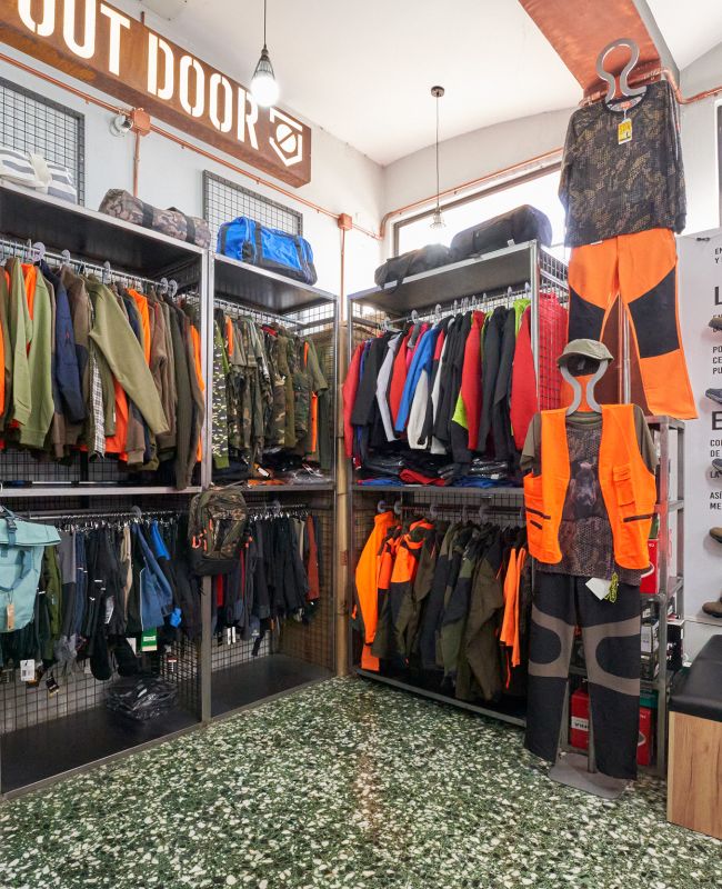 Interior de tienda de ropa laboral con uniformes, chaquetas, chalecos de alta visibilidad y calzado de seguridad para profesionales.