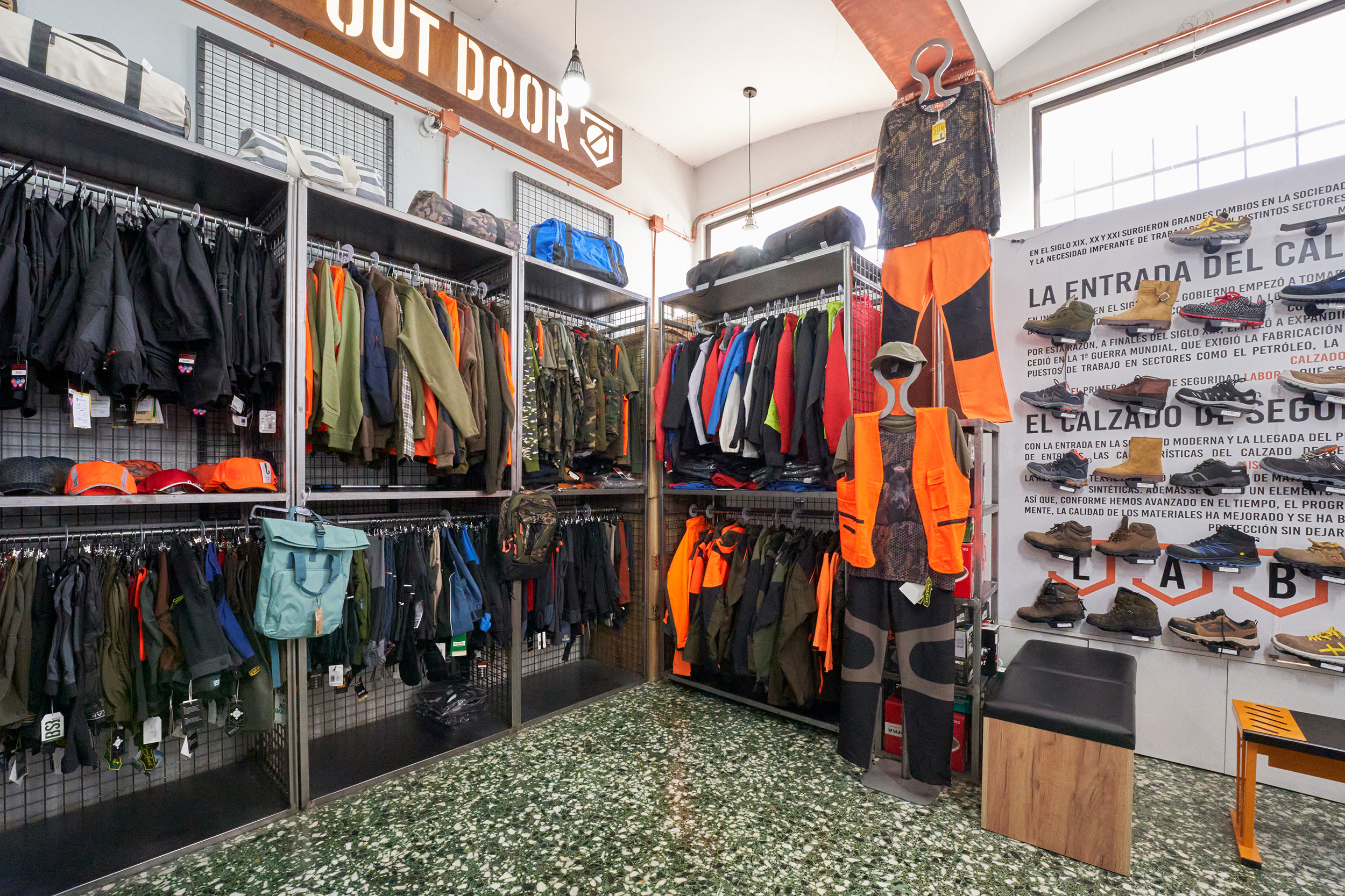 Interior de tienda de ropa laboral con prendas de alta visibilidad, calzado de seguridad y uniformes para profesionales.