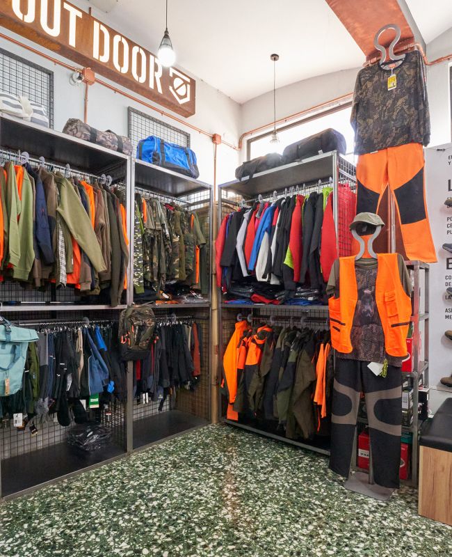 Interior de tienda de ropa laboral con uniformes, chaquetas, chalecos de alta visibilidad y calzado de seguridad para profesionales.