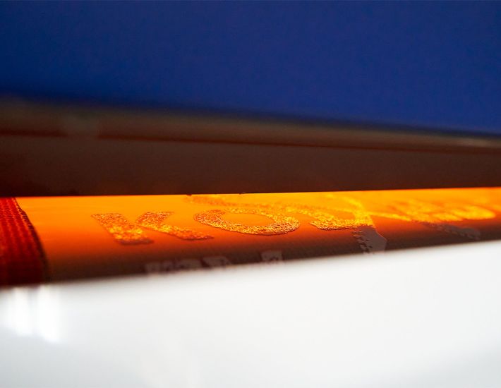 Máquina industrial de impresión DTF con bandeja frontal azul y ventiladores, utilizada para personalizar ropa laboral con alta precisión y calidad.